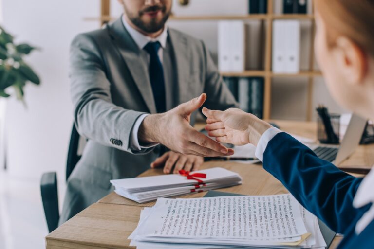 Un professionista stringe la mano a una cliente dopo aver esaminato la documentazione